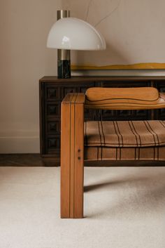 a wooden bench sitting next to a lamp on top of a white carpeted floor