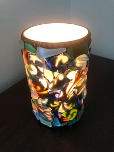 a colorful glass vase sitting on top of a wooden table next to a white wall