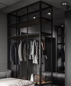 an open closet with clothes hanging on the wall and a bed in the foreground