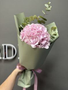 a hand holding a bouquet of pink flowers