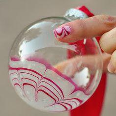 a woman's hand holding a glass ornament with pink and white designs