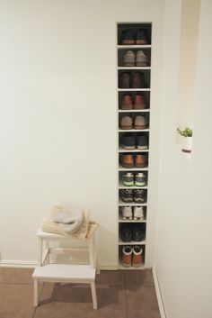 a small white bench sitting in front of a book shelf filled with books and shoes