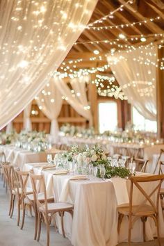 the tables are set up with white linens and lights strung from the ceiling above them