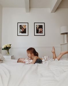 two young children laying on top of a bed next to each other in a bedroom