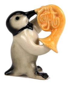 a figurine of a penguin playing the french horn with an orange piece in its mouth