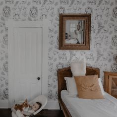 a baby laying in a bed next to a white door and wall with animals on it