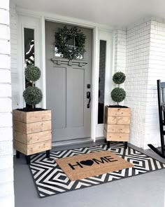 a front door with two planters and a welcome mat on the floor next to it