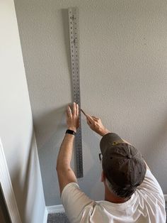 a man measuring the height of a wall with a tape measure on it's side