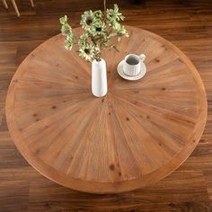 a wooden table with two vases and a white cup on it, sitting on top of a hard wood floor