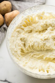 a bowl filled with cream next to potatoes