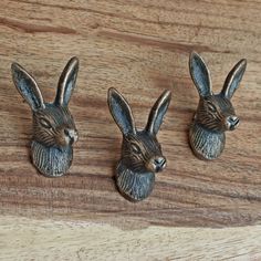 three metal rabbits sitting on top of a wooden table