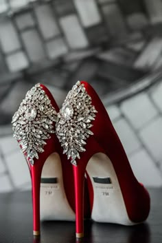 a pair of red high heeled shoes with jewels on them