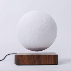 a large white ball sitting on top of a wooden stand next to a black cord