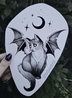 a person holding up a guitar pickle with a cat and bat design on it