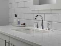 a bathroom sink with two faucets and a soap dispenser on the counter