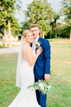 a bride and groom pose for a photo in front of the trees at their wedding