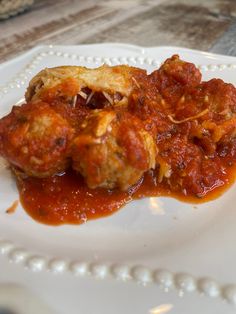 a white plate topped with meatballs covered in marinara sauce on top of a wooden table