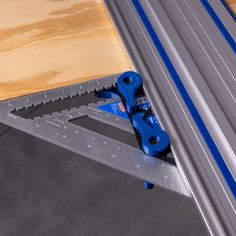 a pair of blue pliers sitting on top of a piece of metal under a wooden table