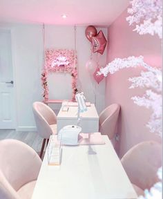 a room with pink chairs and balloons on the wall, in front of a white table