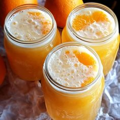 four mason jars filled with orange juice and garnished with an orange slice on top