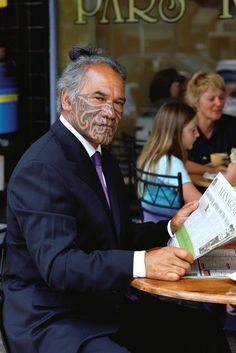 a man sitting at a table reading a newspaper