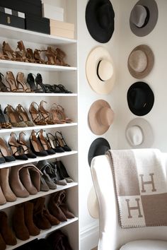 a white chair sitting in front of a shelf filled with hats and shoes on it