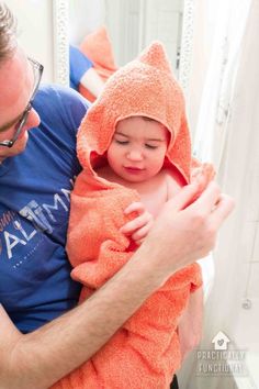 a man holding a baby wrapped in a towel