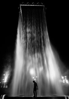 a man standing in front of a fountain at night