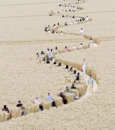 many people are sitting on bales in the sand