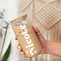 a woman holding a drink with the word coco cola on it in front of her face