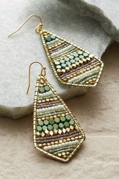 two pairs of earrings sitting on top of a rock