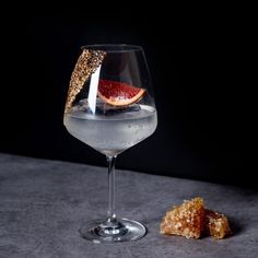 a wine glass filled with liquid and garnished with grapefruit on the side