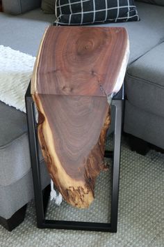 a wooden table sitting on top of a metal frame in front of a gray couch