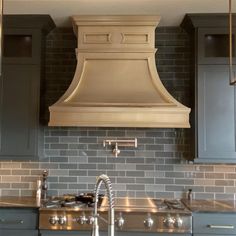 a kitchen with gray cabinets and an oven hood