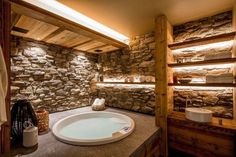 a bathroom with stone walls and a large jacuzzi tub in the middle of it