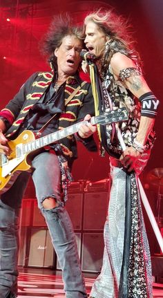 two people on stage with guitars and microphones