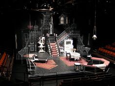 an empty stage with chairs, tables and stairs on it's sides in the dark