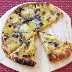 a sliced pizza sitting on top of a cutting board next to a slice of lemon