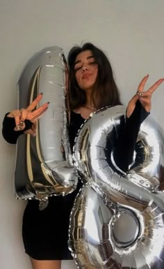 a woman holding two large silver balloons in front of her face