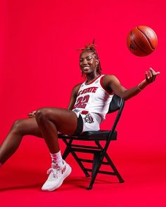 a woman sitting on a chair with a basketball in her hand