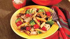 a yellow plate topped with pasta and vegetables next to a red bowl filled with rice