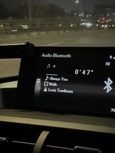 an electronic device on the dashboard of a car at night time with lights in the background