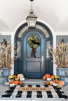 a blue front door decorated for fall with pumpkins and gourds