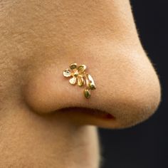 a close up of a person's nose with gold flowers on it