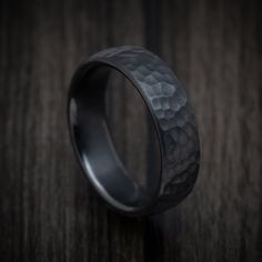 a black wedding ring on top of a wooden table with dark wood in the background