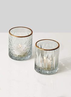 two clear glass tumblers with gold rims on a white table top next to each other