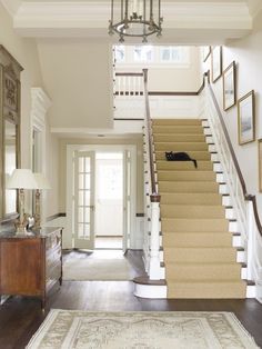 an entryway with stairs and pictures on the wall, carpeted flooring and chandelier