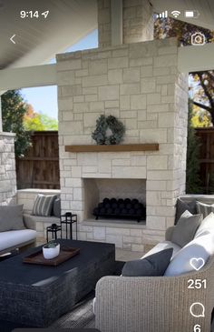 a living room with couches, chairs and a fire place in front of a brick wall