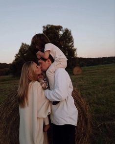 a man and woman kissing while standing next to each other in front of hay bales