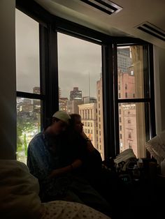 two people are sitting in front of large windows looking out at the cityscape